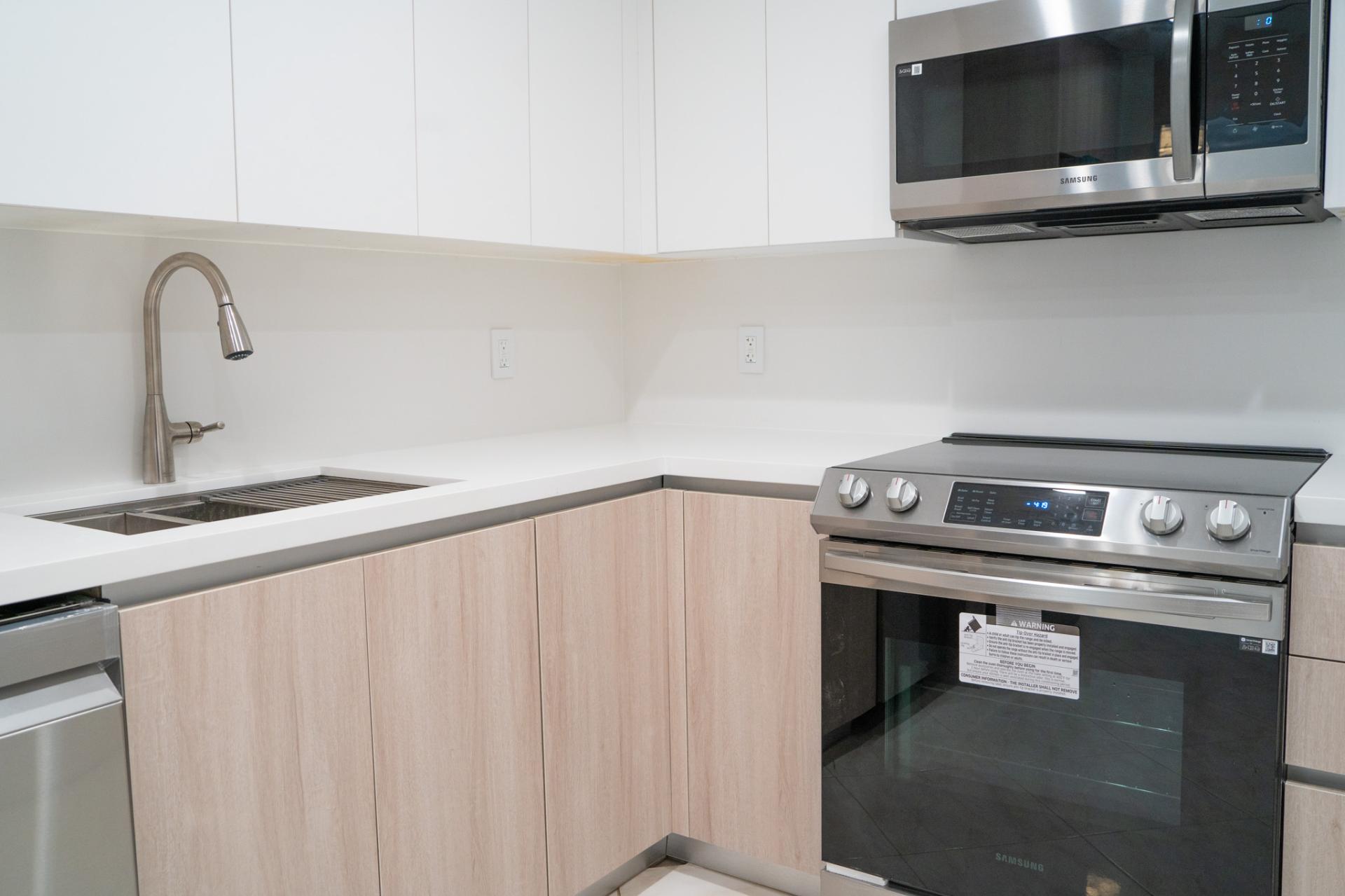 Contemporary coastal kitchen cabinet detail with pale wood lower cabinets